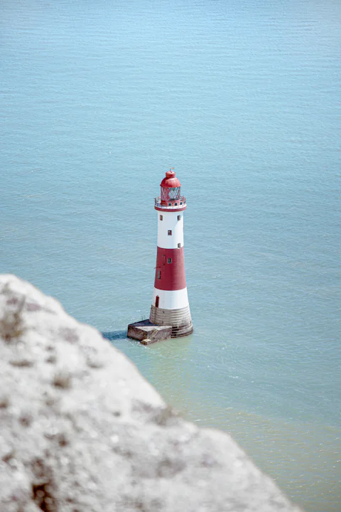 A red and white lighthouse over turquoise water
